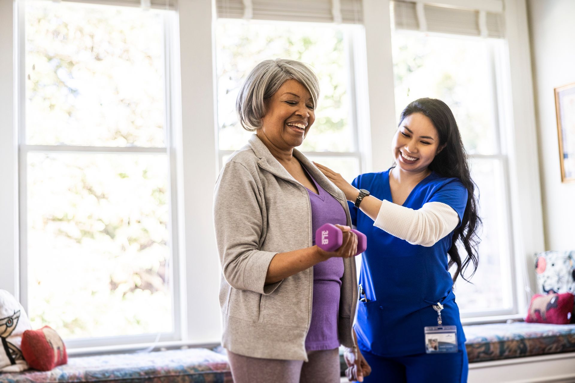 Older adult lifting dumbbell with help from healthcare professional.